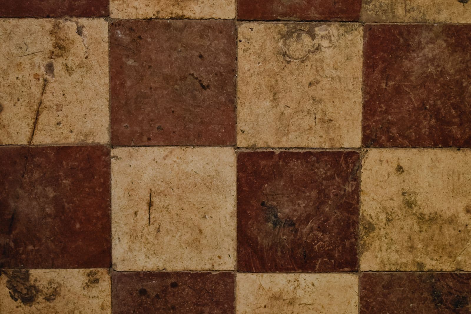 Abgetretener Boden aus quadratischen braunen und beigen Platten im Schachbrettmuster