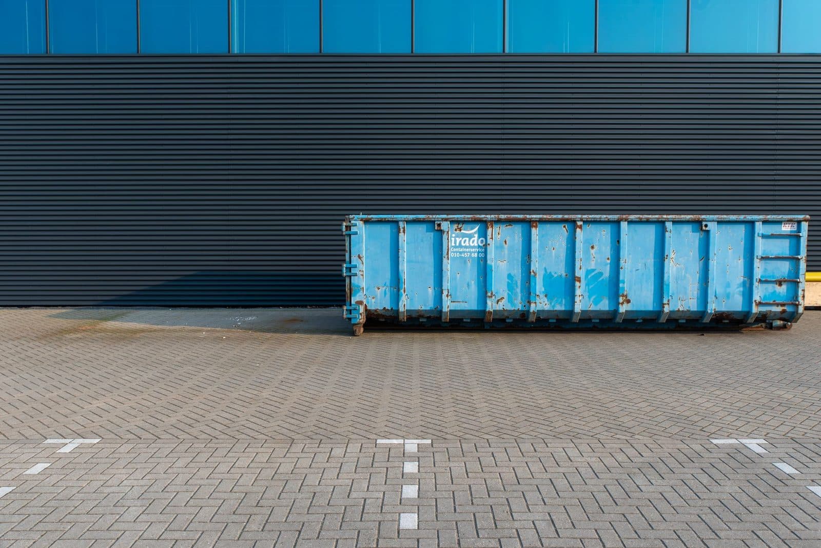 Blauer Abrollcontainer vor einer Halle